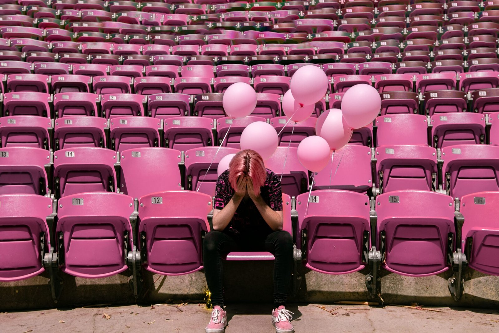 a person sitting on a bench in front of a bunch of pink chairs